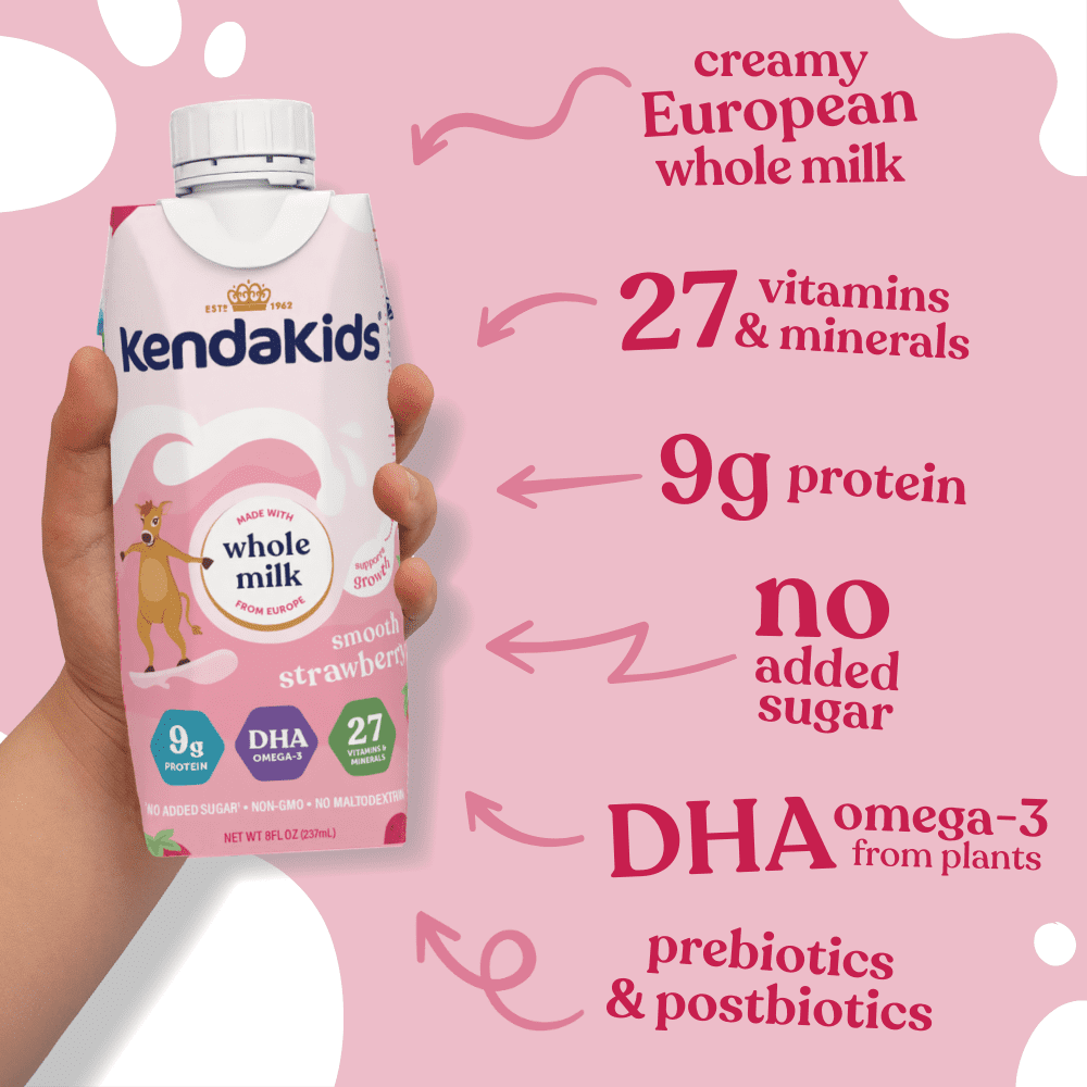 Hand holding a strawberry-flavored nutritional drink carton with text and arrows indicating ingredients and benefits