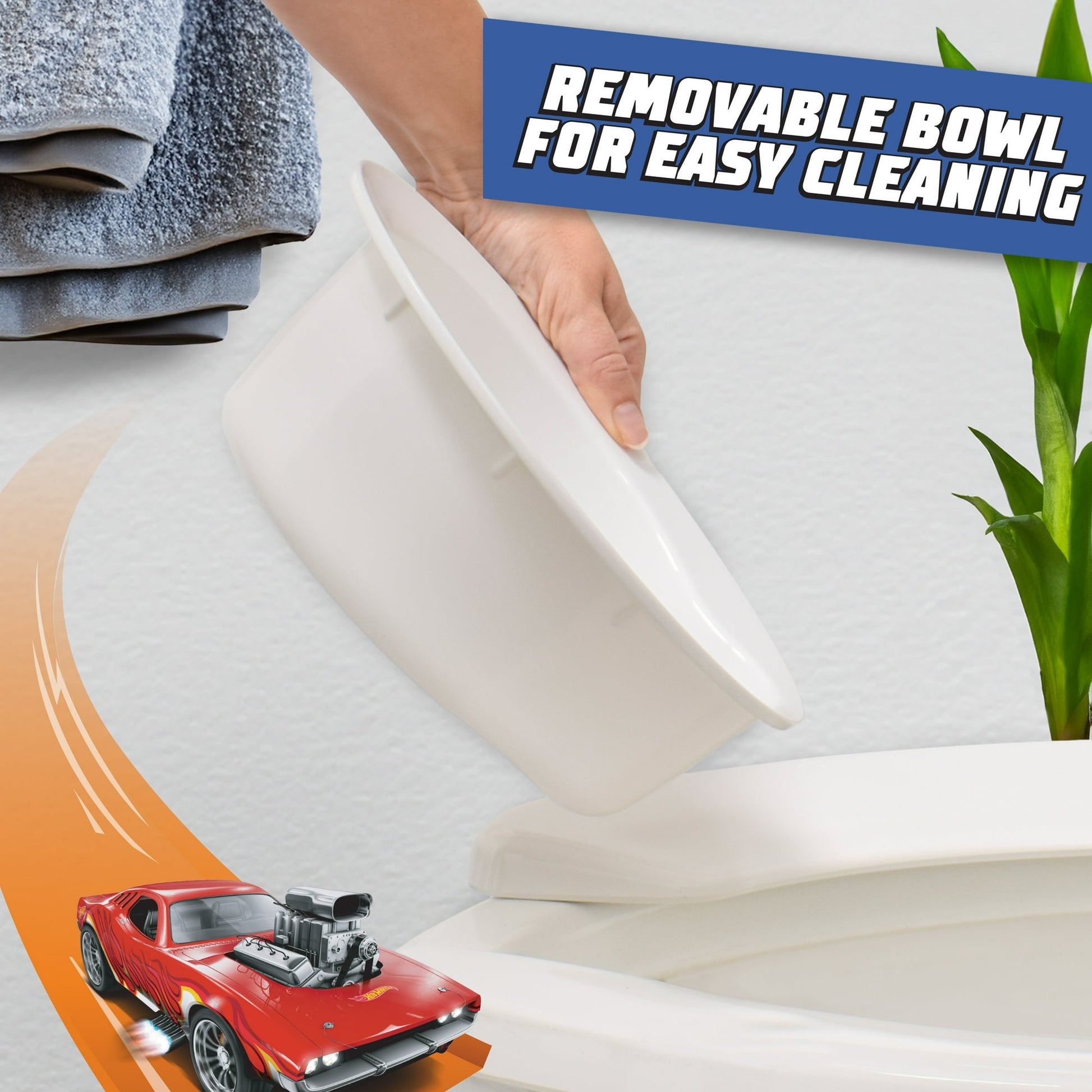 An image showing a white removable bowl being lifted from a toilet training seat, with a toy race car and towels visible