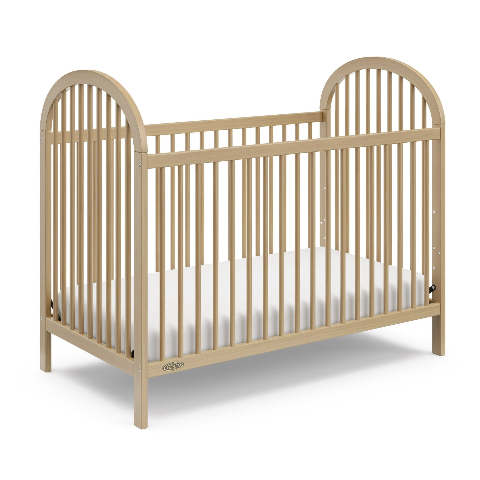 A light-colored wooden baby crib with a white mattress inside