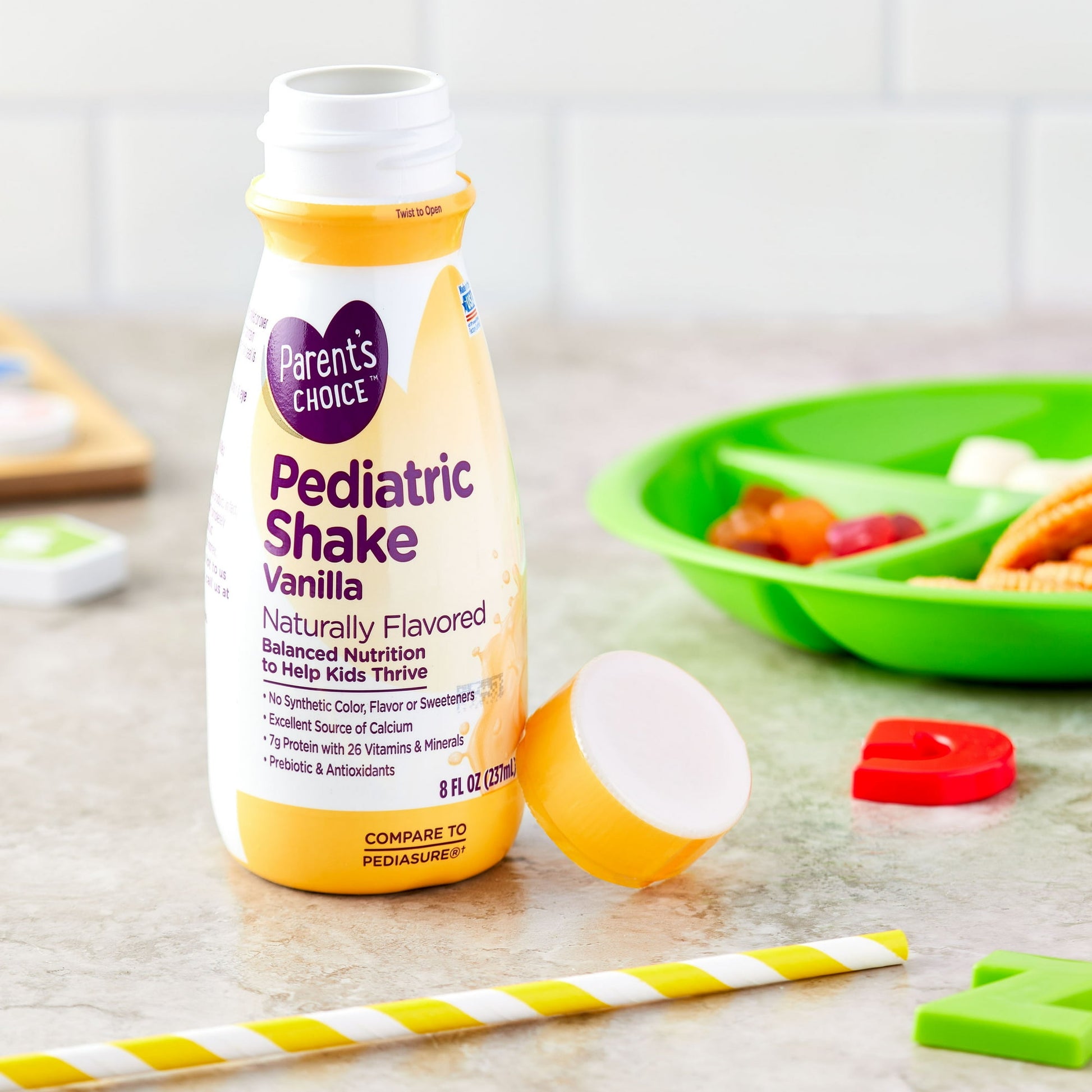 Kids vanilla pediatric shake bottle with a straw and child's meal items on a table